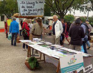 Tables et banderolle sur le marché de Coustellet sur la question de l'accès à la terre pour les paysans